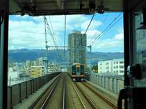 Hanshin Konzern: Der Schnellzug 9203 (Serie 9200, Baujahr 1996) in der typischen Landschaft zwischen Ôsaka und Kôbe, am Fusse des Rokkô-Gebirges. Hier im relativ vornehmen Ortsteil von Kôbe in Nishinomiya ist die Bahn bereits zur Hochbahn umgebaut. 22.März 2014. (Bild durch die verglaste Führerstandrückwand eines Gegenzugs) 