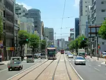 Die Strassenbahn von Nagasaki - die Innenstadt jetzt: Wuchtige moderne Bauten haben hier das alte Chaos verdrängt, doch wie durch ein Wunder ist die Strassenbahn noch da. Der  alte Wagen 364, der meinem Wagen folgt (Bild nach hinten aufgenommen), ist noch eine echte Rumpelkiste, wogegen ein moderner Gelenkwagen (Wagen 3002) gerade gekreuzt hat. 8.August 2013.  