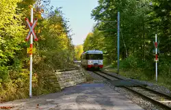 Der BDe 4/4 3 der TPN überquert am 07.10.2025 auf seiner Fahrt von Le Locle nach Les Brenets einen Bahnübergang am Haltepunkt Les Fretes