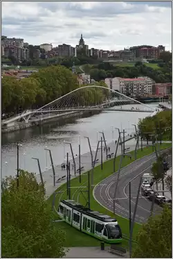 CAF Tram beim Guggenheim Museum am Ufer des Nervión mit der Fussgängerbrücke von Santiago Calatrava.
