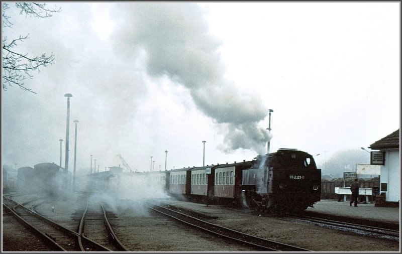 Whrend 99 2321-0 mchtig Dampf macht, rollt dahinter auf den Normalspurgleisen ein Rbenzug durch den Bahnhof Bad Doberan. (Archiv 11/90)