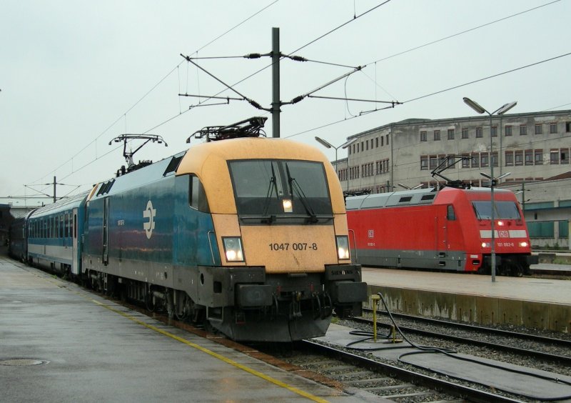 Whrend die MAV 1047 007-8 in Wien Westbahnhof am 20. Mai 2008 die Kurswagen des EN - Wienerwalzers Zrich - Budapest bernimmt, wartet die DB E 101 mit einem EC nach Mnchen. rgerlich, aber unvermeidbar: die Lampenstange vor der DB Lok...
