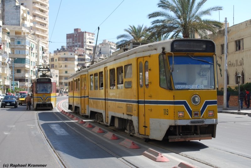 Wagen 119 und 120 der Yellow Line in Alexandria. Auf der Yellow Line wird mit Stangenstromabnehmern gefahren. Die Fahrt mit diesen Dinosauriern ist ein Erlebnis, aber Jungs, bitte hinten einsteigen! Vorne ist f�r Frauen reserviert (das wei� ich auch erst, nachdem ich vorne rausgeflogen bin :-) ). Im Hintergrund der Tatort meines Vergehens: Der Zweisystemwagen, mit welchem ich Richtung Innenstadt fuhr. Tatzeit: 15.04.09