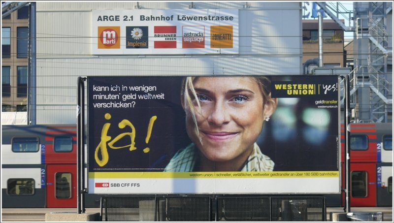 Western Union, eine Dienstleistung, die jeder grssere Bahnhof in der Schweiz anbietet. Werbetafel vor der Baustelle zum neuen Durchgangsbahnhof Lwenstrasse in Zrich HB. (16.05.2009)