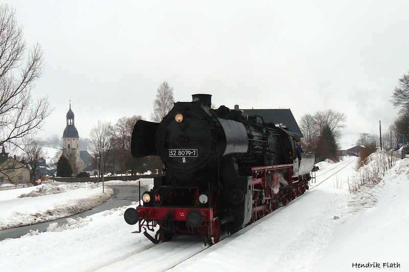 Whrend 119 158 in Cranzahl blieb machte sich 52 8079-7 auf den Weg nach Schwarzenberg um dort einen Wagen abzuholen. Entstanden ist diese Aufnahme am 28.02.2009 in Schlettau. Im Hintergrund ist die St. Ulrich Kirche zusehen.