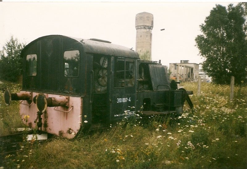 Wie jedes Bw hat auch das Bw Seddin einen Bereich wo ausgemusterte Loks abgestellt sind.Mit dem ehmaligen Wahrzeichen vom Bw Seddin dem Wasserturm im Hintergrund steht die K� 310 897  1998 abgestellt und wartet auf die Verschrottung.�brigens der Wasserturm wird noch auf vielen Bildern zusehen sein.Leider existiert der Wasserturm Heute nicht mehr.