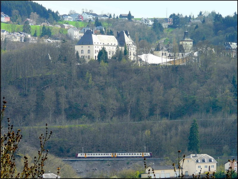 Wieder ein Beispiel, wie klein die Eisenbahn ist! RB 3215 fhrt vor der Kulisse des Schlosses von Wiltz (12. Jahrhundert) in Richtung Bahnhof. Unter dem weien Zeltdach findet alljhrlich im Sommer ein Musikfestival statt. Das Bild wurde am 24.04.08 von der Route d'Erpeldange in Weidingen gemacht. 