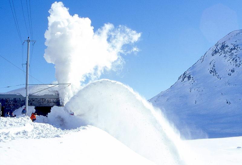 X rot d 9213 DAMPFSCHNEESCHLEUDER im Schleudereinsatz am 08.02.1997 direkt an der Depotausfahrt Ospizio Bernina - Baujahr 1911 - SLM - 63,5t Dienstgewicht - LP 13,67m - V = 35km/h - Schleudern mit 12km/h - Trichterbreite von 3,80 bis 3,25m einstellbar - Mutation: ex Berninabahn G 2x3/3 1051 - 1943 RhB X rot d 13 - 1954 X rot d 9213 Hinweis: wunderschner seltener gleichmiger Schleuderauswurf des Schnees in den seitlichen Abgrund. Gegenlichtaufnahme. 