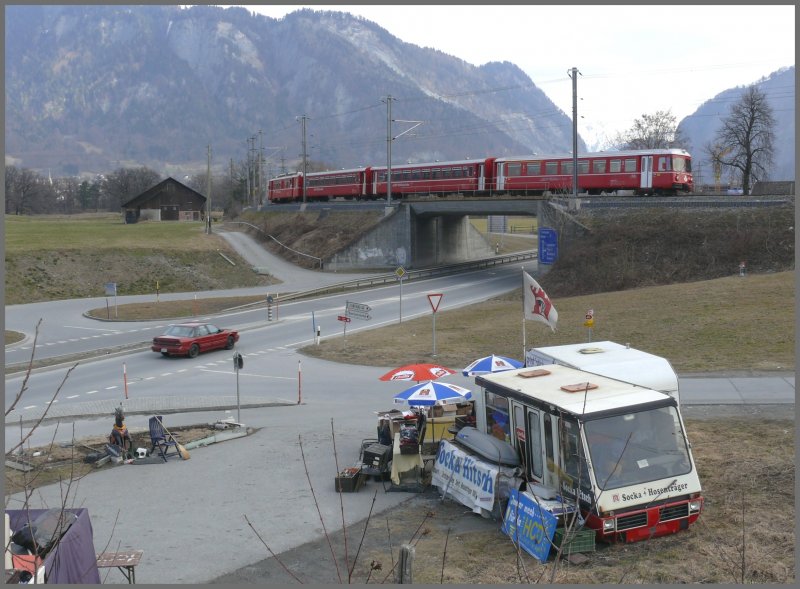 Zum Bahnhof Landquart gehrt der Socken-Hitsch, ein Bndner Original, der unweit der Autobahnausfahrt seinen Verkaufsstand betreibt. Ein Be 4/4 Pendel berquert soeben die Strasse nach Davos auf dem Weg nach Schiers. (21.02.2008)