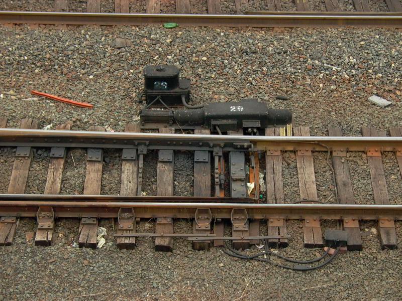 Zungenvorrichtung einer einfachen Weiche mit elektropneumatischem Weichenantrieb im Bahnhof Philadelphia. Im Unterschied zu einer deutschen Weiche sind die Weichenzungen nicht einzeln beweglich sondern wie bei einer Modellbahnweiche starr gekuppelt. Der turmartige Aufsatz auf dem Weichenantrieb enthlt die elektromagnetisch gesteuerten Druckluftventile (Januar 2004). 