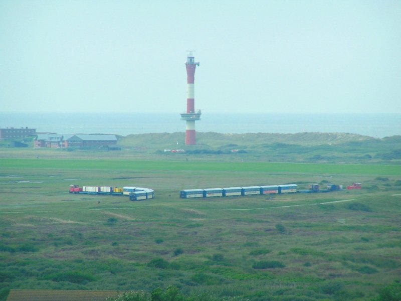 Zwei Zge auf offener Strecke: 
der Zug links ist bereits zu 100% ausgelastet und am Weg zum Hafen;

der Zug rechts hat Jugendliche vom Schullandheim (Gleisanschluss) abgeholt und schiebt die Garnitur nun in den Bhf. Wangerooge um weitere Fahrgste zur Fhre aufzunehmen. (2006-09-02)