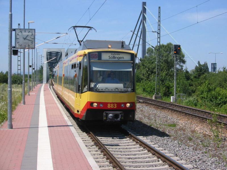 Zweisystem-Stadtbahn des Karlsruher Verkehrs Verbundes (KVV) am 22.06.2003 am Haltepunkt Karlsruhe Maxau. Der Zug der Linie S 5 kommt auf DB-Gleisen aus Wrth am Rhein in Rheinland Pfalz, hat gerade die Brcke ber den Rhein berquert und wird weiter in Richtung Karlsruhe Innenstadt und dann nach Sllingen fahren. Kurz hinter diesen Haltepunkt wird der Zug die DB-Gleise verlassen und in das Karlsruher Straenbahn-Netz berwechseln.