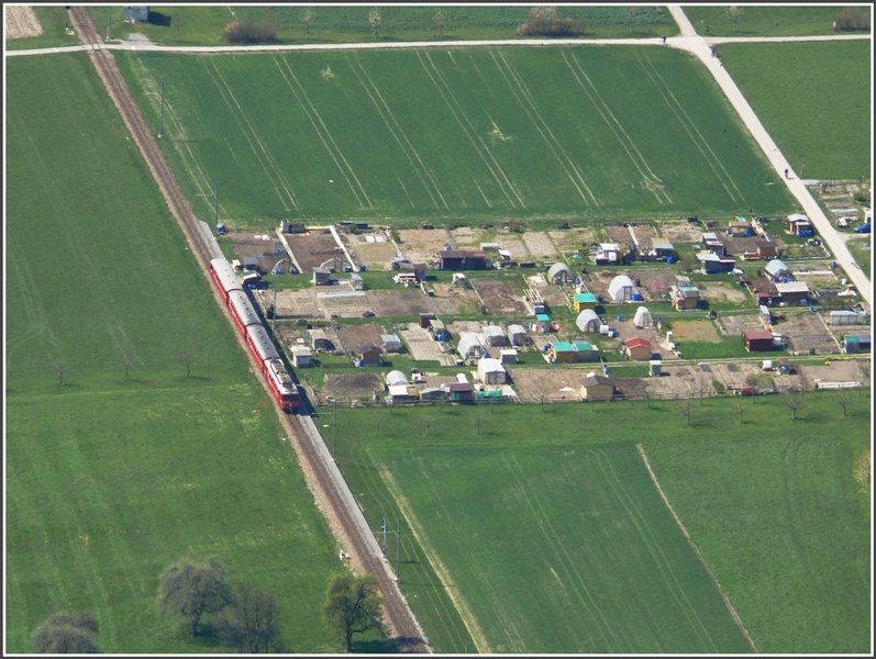 Zwischen Malans und Landquart fhrt ein Be 4/4 Triebzug an einer Schrebergrtenansammlung vorbei. Fotografiert vom Fadrastein aus. (13.04.2008)